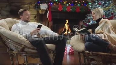 圣诞之夜，快乐的一对夫妇在看书和使用智能手机时聊天